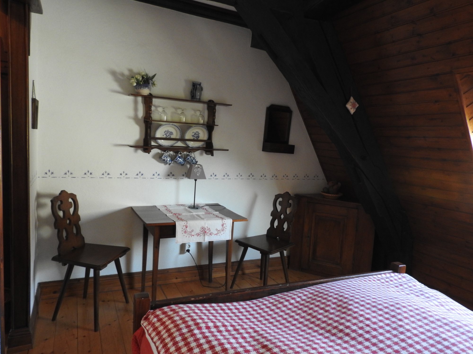 La table et ses deux chaises sculptées, au pied du lit